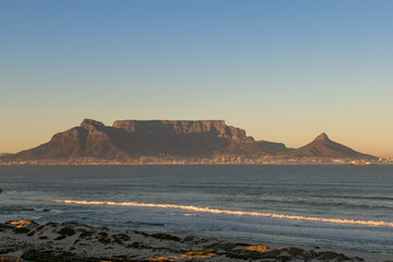 Table Mountain with blue and yellow sky during sunset seen from Bloubergstrand in Cape Town, Western Cape, South Africa - obrazy, fototapety, plakaty