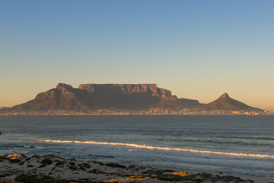 Table Mountain with blue and yellow sky during sunset seen from Bloubergstrand in Cape Town, Western Cape, South Africa