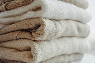 cozy milky beige and white natural wool sweaters, folded on a white background close-up. clothes made of merino wool, alpaca, natural eco-fabrics. the concept of conscious consumption. mockup