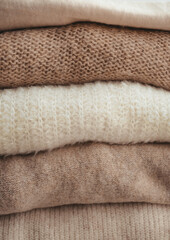 Fototapeta na wymiar cozy milky beige and white natural wool sweaters, folded on a white background close-up. clothes made of merino wool, alpaca, natural eco-fabrics. the concept of conscious consumption. mockup