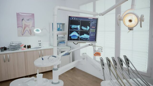 Empty stomatology orthodontic office room equipped with professional dentistry tools ready for medical teeth surgery. Tooth xray images on monitor reveal teethcare diagnosis. Wide to zoom out in shoot