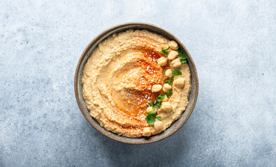 hummus in a ceramic bowl on a blue background, top view, copy space