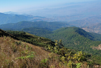 Fototapeta na wymiar Natural landscape of green mountain range with misty summit hill