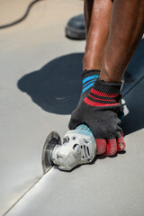 Worker in gloves with a small angle grinder cuts fibre cement, concrete plate in construction site....