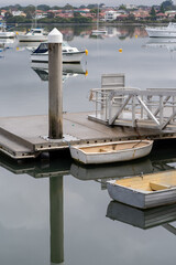 rowing boats docked at wharf pier with reflections on water