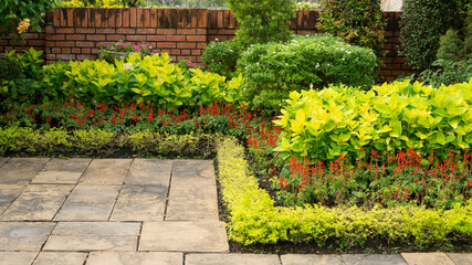 Backyard English cottage garden on brown pavement and green lawn