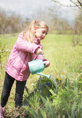 Little girl in a garden with watering pot