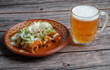hero, side view, horizontal potato and beef fried tacos, in a Mexican mud plate with cream lettuce tomato salsa and onions with lemon on top with a jar of cold beer on the side. Tacos dorados concept.