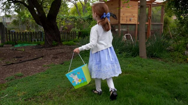 First -person view of little girl having fun with easter egg hunt in garden backyard