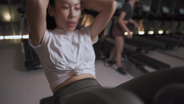 Active young asian woman doing abdominal crunch on the bench, getting six packs abs, self inspire fitness motivation, focus concentration flex muscle, abdominal crunches exercise at indoor fitness gym