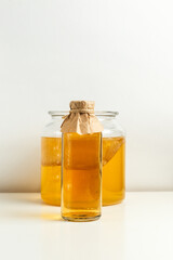 Homemade Kombucha lemonade in a bottle and a jar with a mushroom on a light background.Vertical, copy space