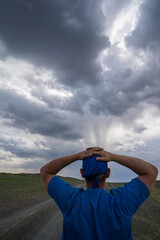 a man looking at a tornado in a stormy sky over a dirt road in mongolia, vertical placement