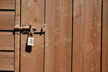 Simple metal code lock on a wooden brown color shed door. Safety and security concept. Peace of mind for the owner