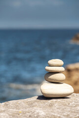 Stack of balance stones by the ocean. Burren, Ireland. Warm sunny day. Selective focus. Pyramid of pebble in nature environment.