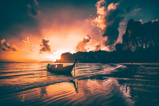 Amazing sunset with longtail boats silhouette at Railay beach, Thailand.