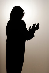 Silhouette of muslim woman in abaya prays with her hands up in air. Religion praying concept.  United Arab Emirates