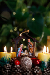Christmas crib and natural advent wreath or crown  with four burning yellow  candles.  Christmas...