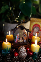 Christmas crib and natural advent wreath or crown  with four burning yellow  candles.  Christmas composition.  France.