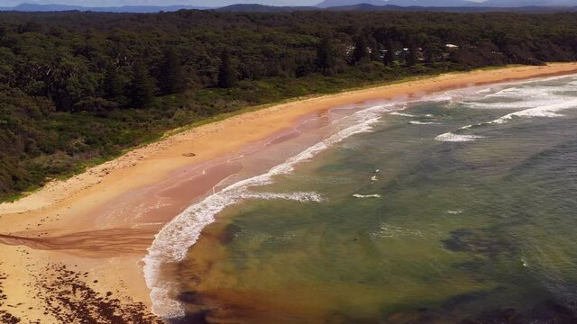 Beach flyby over rolling waves