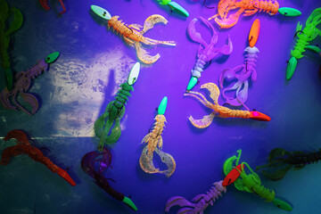 Silicone bait for catching predatory fish is painted with phosphoric paint. Demonstration of modern technologies using ultraviolet rays. Flat lay of the frame