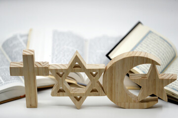 The three monotheistic religions. Christianity, Islam and judaism. Thorah, Quran and Bible with croos, star of David and muslim crescent.  Interreligious or interfaith symbols. France.