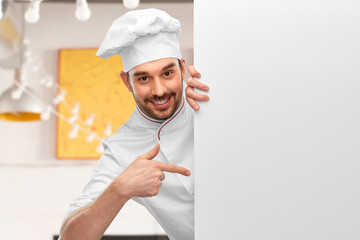 cooking, culinary and people concept - happy smiling male chef in toque pointing finger to big white board over restaurant background