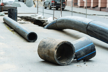 Installation of the city sewerage system. Large diameter plastic pipes lie on the asphalt near the...
