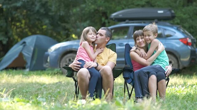 Parents and their children sitting together and hugging happily. Happy family enjoying time at capmsite outdoors.