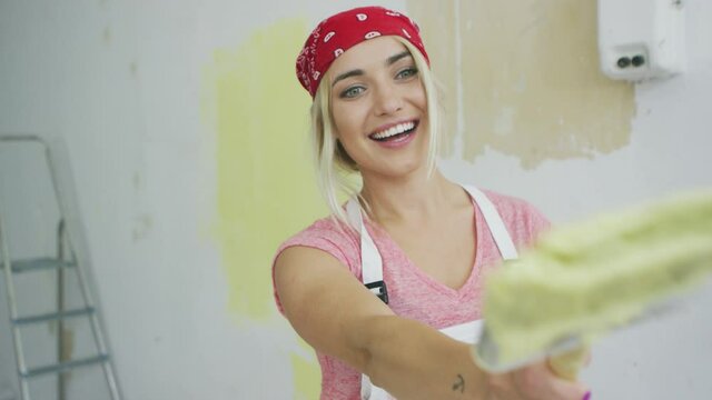 Happy female painter pointing with brush