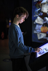 A boy uses an interactive touchscreen displayed in the museum. Education, technology and future...