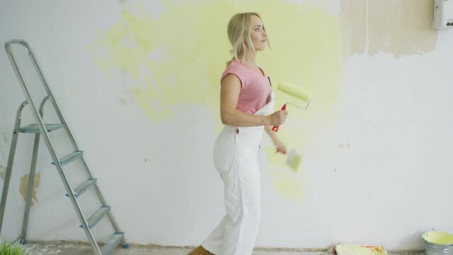 Relaxed woman dancing with paint roller