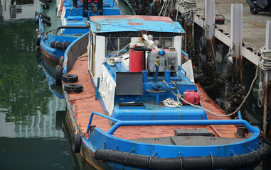Fototapeta na wymiar A blue work boat moored in the harbor