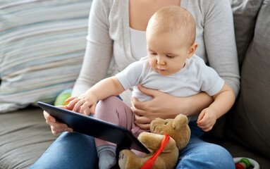 family, motherhood, technology and people concept - mother and little baby daughter with tablet pc computer at home