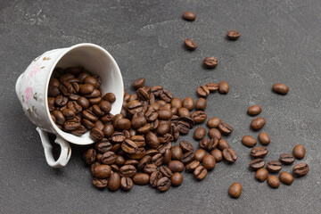 Roasted coffee beans are scattered from cup onto table