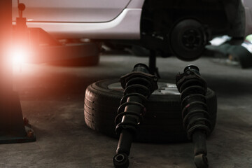 Auto mechanic maintaining a car shock absorbers at garage station. - 434882075