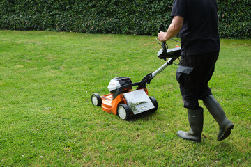gardener mowing the lawn with a lawn mower