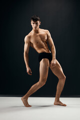 Obraz premium man with a pumped-up body holds his hands above his head posing dark panties