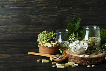 Concept of herbal medicine pills on wooden table, space for text