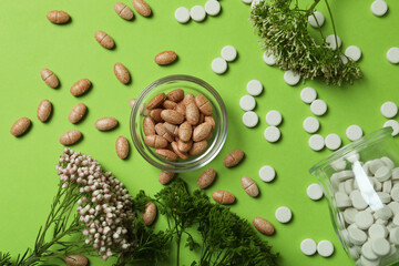 Fototapeta na wymiar Concept of herbal medicine pills on green background, top view