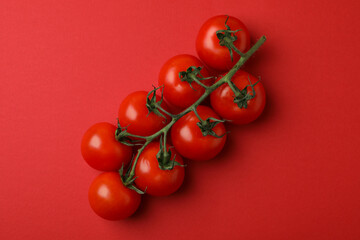 Fresh cherry tomato branch on red background