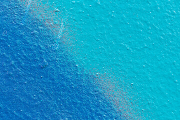 Macro close-up of a spray painted blue and turquoise wall with splashes. Abstract full frame textured splattered graffiti background with copy space.