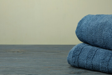 Clean folded towels on gray wooden table, space for text