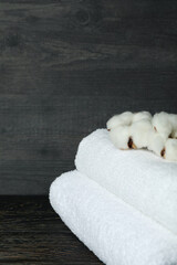 Clean folded towels with cotton on wooden background, close up