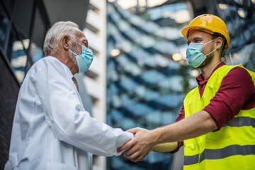 Engineer, and doctor on street handshaking.