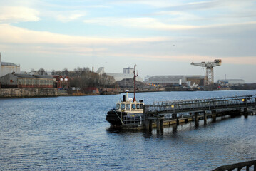 Small Boat Moored at Jetty on Rippled Waters of River & Distand Industrial Area