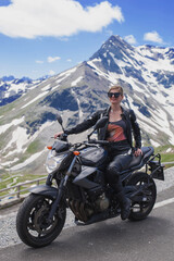 black naked motorcycle is parked on the side of serpentine mountain alpine road