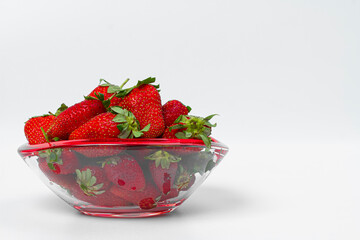 Ripe, fresh strawberries in a glass vase on a light background. Copy space.