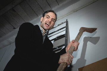 A psychopathic madman, young adult, threatens with an old and rusty ax in his hands, while he...