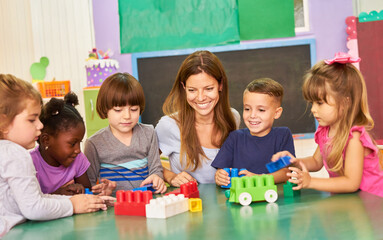 Kindergarten teacher and children play with building blocks