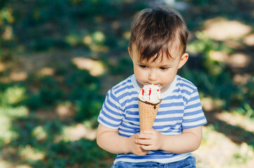 a child in a t-shirt on a bench eating ice cream in the summer, very hot and tasty